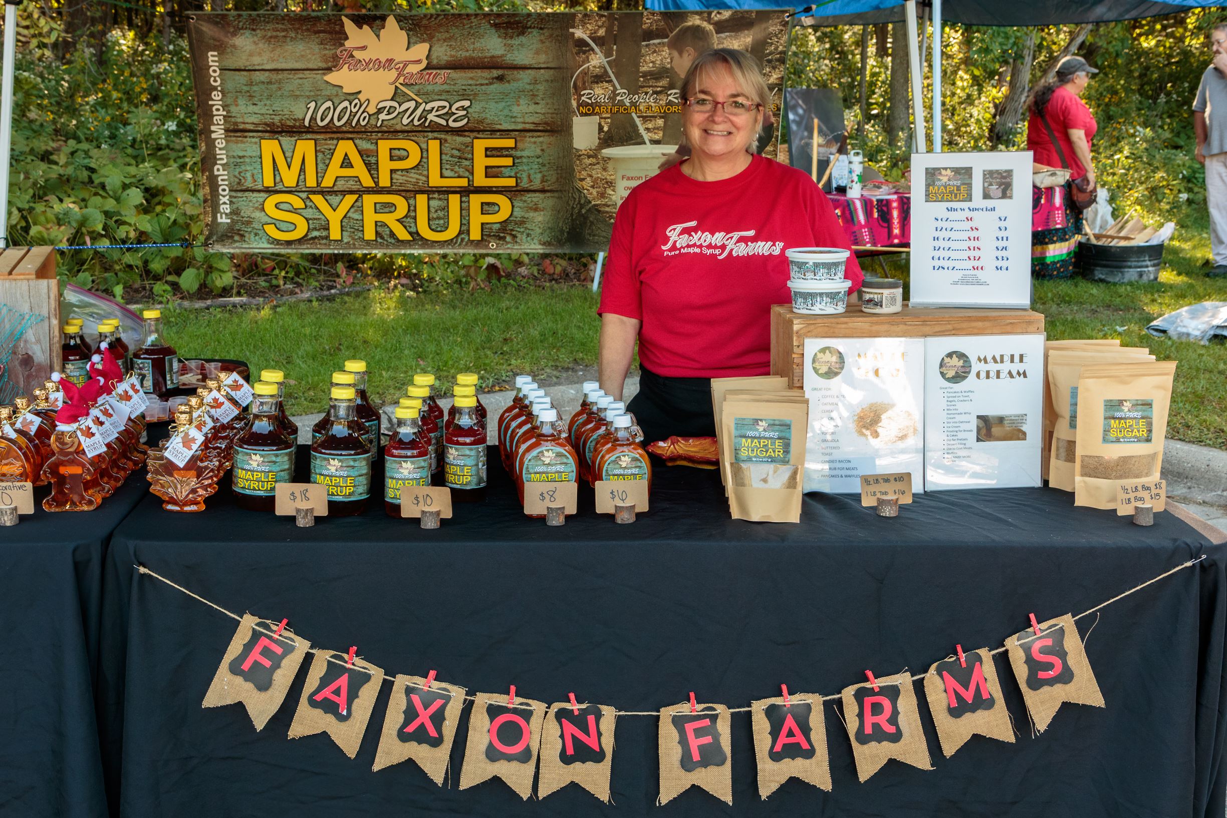 Woman at maple syrup booth with products for sale
